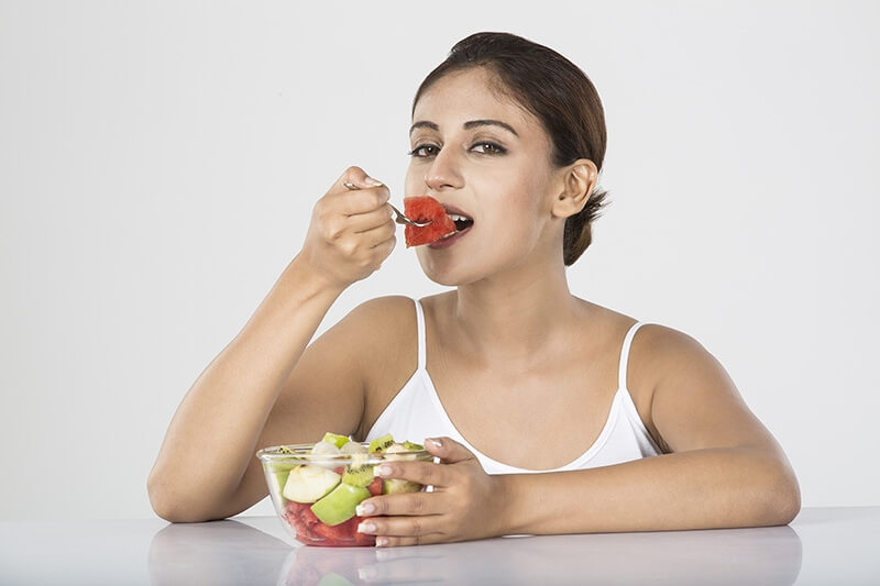 young woman eating fruit salad