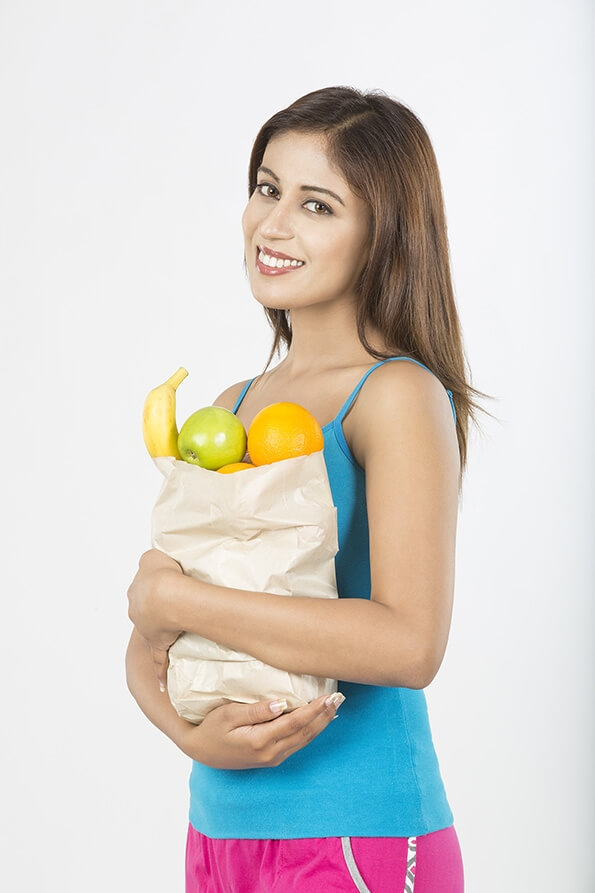beautiful young woman with fruits in shopping bag
