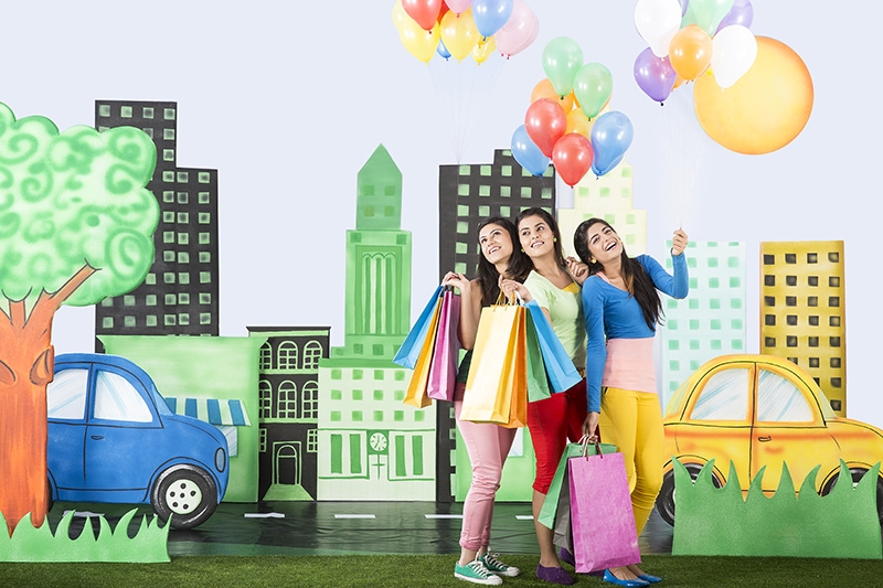 three friends posing with shopping bags and holding balloons