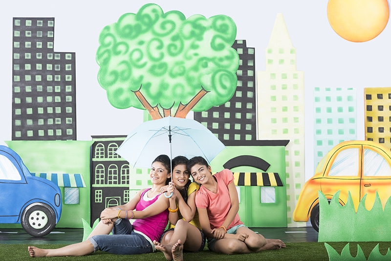 Three girls sitting under an umbrella