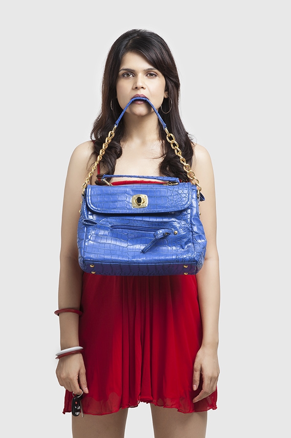 stylish young female carrying a blue handbag while posing