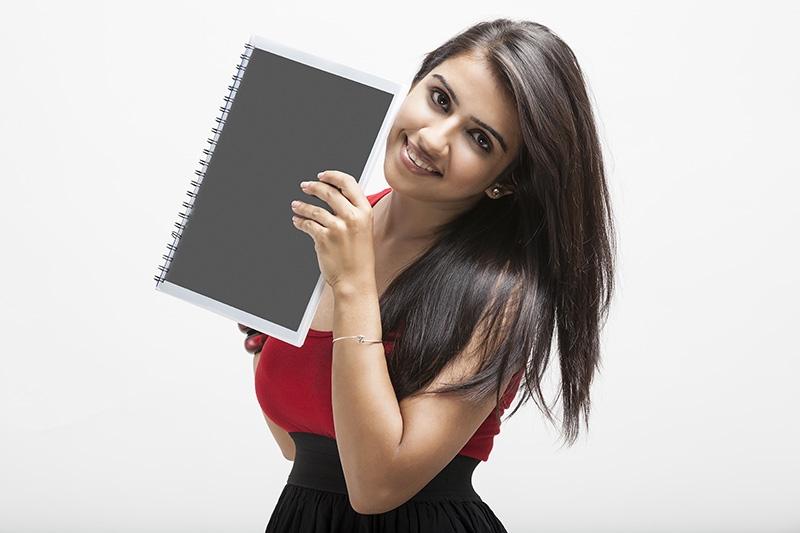 girl posing while holding a text book